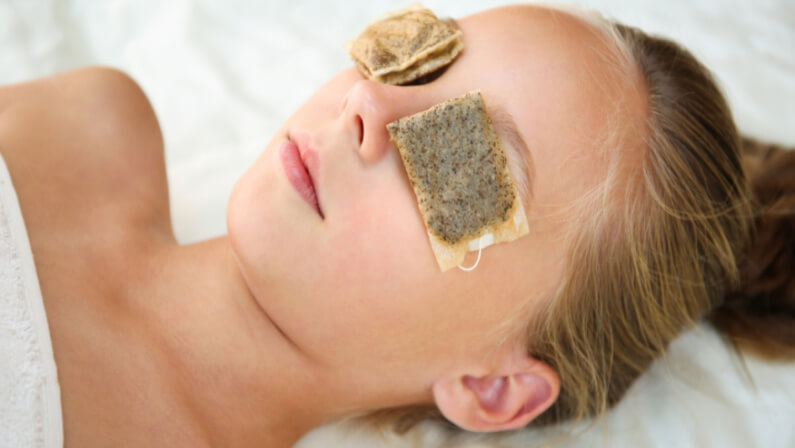 women using tea bags on her eyes